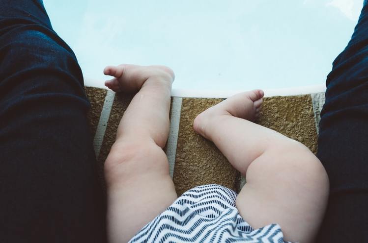 プールサイドに座る赤ちゃんの足